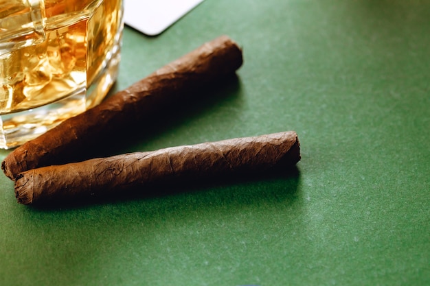 Primo piano di bicchiere di whisky e sigaro su superficie verde