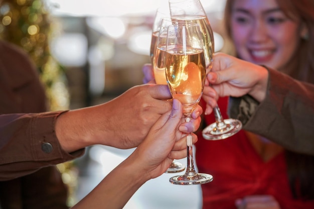 Primo piano di bicchieri di champagne tintinnanti con illuminazione. Cena con bevute di champagne. le mani che tengono il vetro trasparente con alcool in lucentezza gialla riflettono.