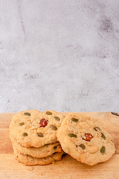 Primo piano di biscotti ai cereali sono impilati sul tagliere, biscotti conditi con mandorle, uvetta, semi di girasole, semi di zucca, cereali integrali.