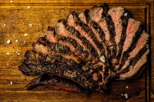 Primo piano di bistecca ribeye disossata a fette servita su una tavola di legno in un ristorante