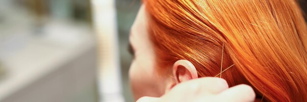 Primo piano di capelli rossi di lusso femminili con la creazione di un parrucchiere professionista di accessori dorati