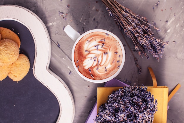 Primo piano di cappuccino alla lavanda con crema di figura nella tazza bianca