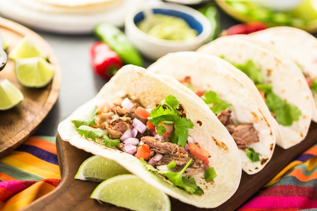 Primo piano di carnitas di maiale tirato con pico de gallo su una tortilla di farina.