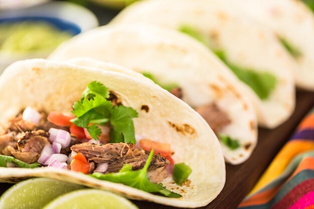 Primo piano di carnitas di maiale tirato con pico de gallo su una tortilla di farina.