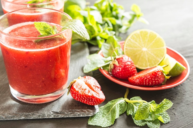 Primo piano di cocktail alla fragola appena spremuti con menta e limone su sfondo nero