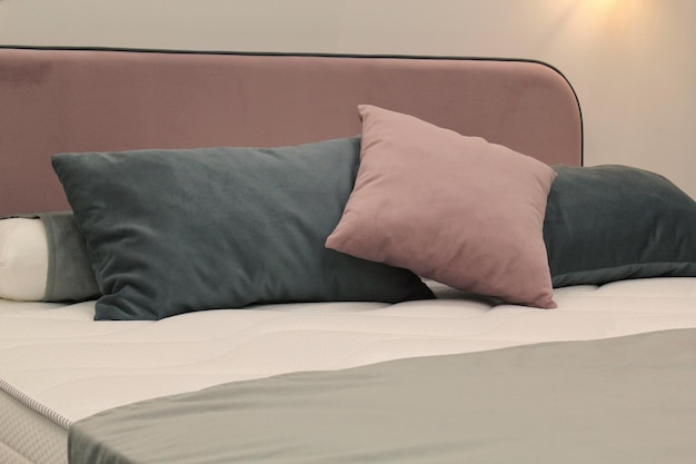 Primo piano di comodi cuscini morbidi colorati sul letto Elegante appartamento alla moda arredamento per la casa Hygge sca