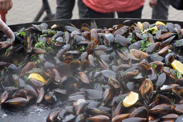 Primo piano di cozze cotte in un festival di cibo di strada pronto a mangiare pesce fotografato con messa a fuoco morbida