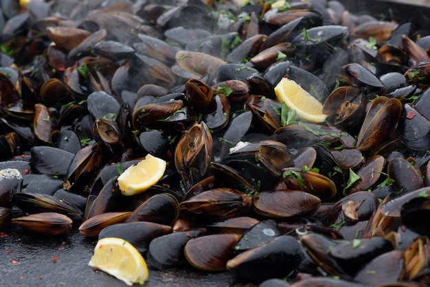 Primo piano di cozze cotte in un festival di cibo di strada pronto a mangiare pesce fotografato con messa a fuoco morbida