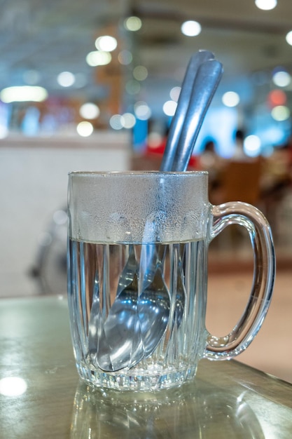 Primo piano di cucchiaio e forchetta d'argento in un bicchiere con acqua