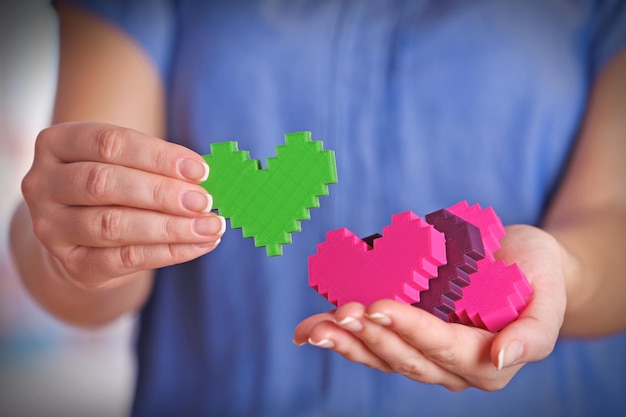 Primo piano di cuori di puzzle di plastica in mani femminili