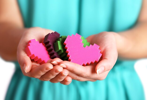 Primo piano di cuori di puzzle di plastica in mani femminili