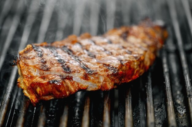 Primo piano di deliziosa bistecca di manzo sulla griglia fiammeggiante