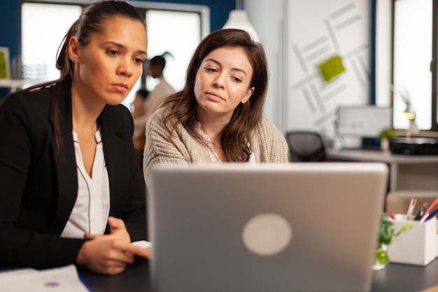 Primo piano di diverse donne d'affari che controllano i grafici dal laptop che creano una nuova strategia per l'avvio dell'attività