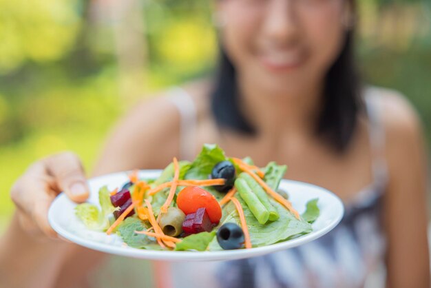 Primo piano di donna alzò un piatto di insalata di verdure Ragazza godetevi l'insalata a pranzo concetto di dieta di benessere Concetto di salute