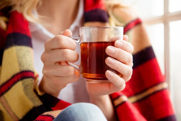 Primo piano di donna che copre con plaid e tenendo la tazza di tè