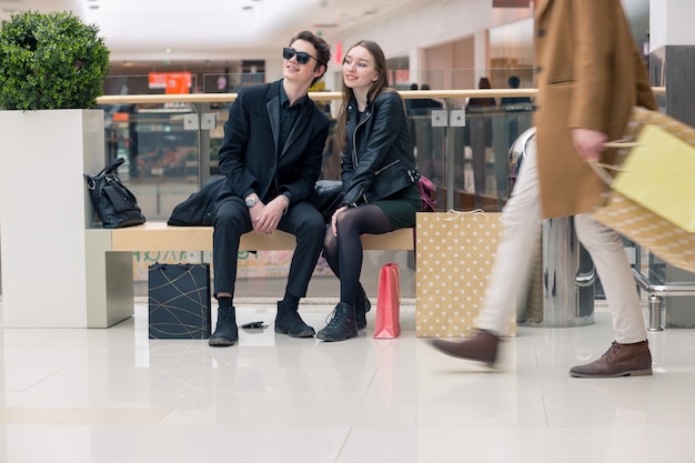 Primo piano di donna e uomo in panchina con colorate shopping bag