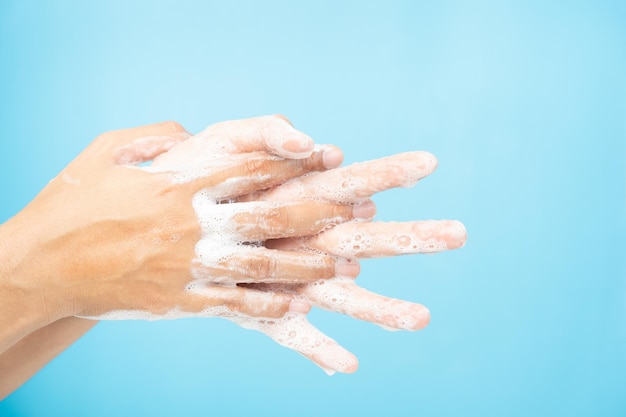 Primo piano di donne asiatiche Pulizia delle mani con bolle di sapone bianche su sfondo blu. Dimostrazione di lavaggio delle mani per la protezione dai virus. Concetti di igiene e prevenzione del covid 19