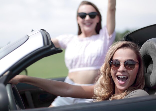 Primo piano di due amiche che viaggiano in uno stile di vita alla moda di un'auto decappottabile