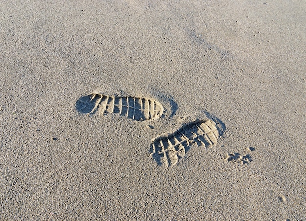 Primo piano di due impronte nella sabbia