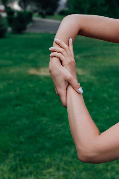 Primo piano di due mani femminili che si tengono su erba verde nel parco, concetto di cura e supporto.