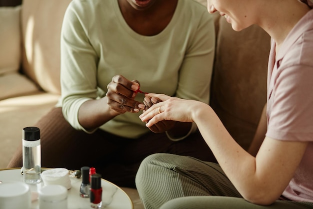 Primo piano di due ragazze che fanno manicure a casa mentre si godono insieme la giornata di cura di sé