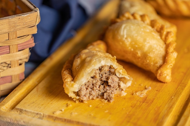 Primo piano di empanada argentina fritta tagliata al centro su una tavola di legno