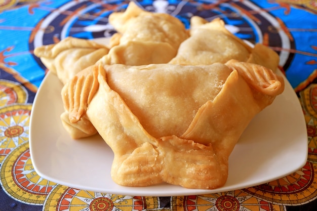 Primo piano di empanadas, deliziosi pasticcini ripieni salati serviti su piastra bianca