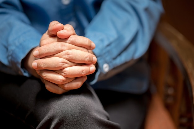 Primo piano di fedeli che pregano, mani giunte in adorazione di Dio. Concetto di religione, fede, preghiera e spiritualità.