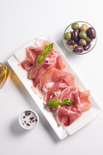 Primo piano di fette sottili di prosciutto con olive miste