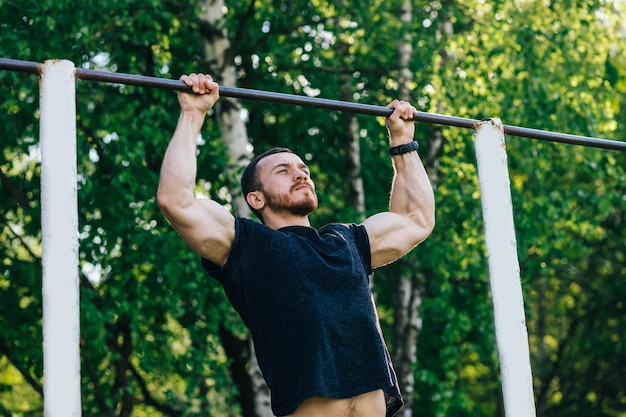 Primo piano di forte atleta che fa pullup sulla barra orizzontale