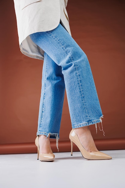 Primo piano di gambe femminili in blue jeans e tacchi alti fantasia beige Pompe in pelle da donna