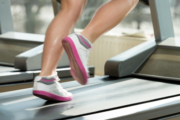 Primo piano di gambe femminili in esecuzione sul tapis roulant movimento sfocato