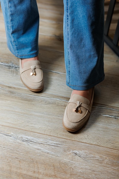 Primo piano di gambe femminili in jeans e mocassini beige in vera pelle