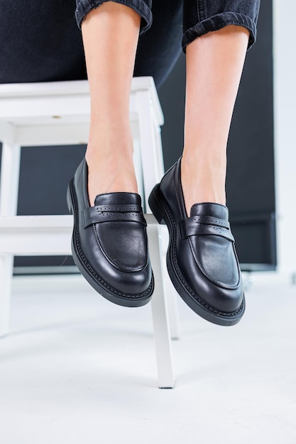 Primo piano di gambe femminili in pantaloni e scarpe chelsea classiche in pelle nera Scarpe estive comode da donna Nuova collezione primavera-estate di scarpe in pelle da donna 2023