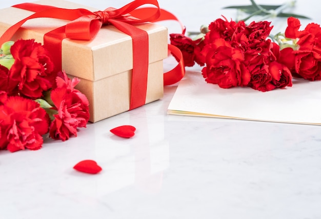 Primo piano di garofano rosso con confezione regalo per la festa della mamma saluto