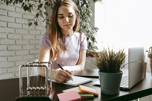 Primo piano di giovane donna di affari che lavora all'ufficio moderno che prende le note