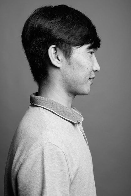 Primo piano di giovane uomo asiatico che indossa la maglietta polo grigia