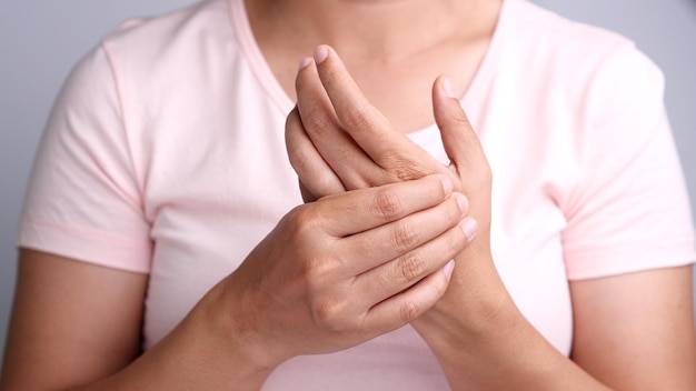 Primo piano di giovani donne asiatiche che soffrono di dolore in mano attorno all'articolazione del dito