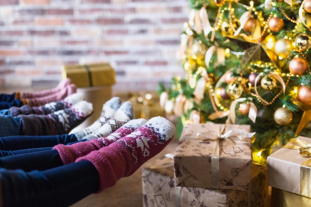 Primo piano di giovani vestiti con calzini natalizi seduti vicino a un albero di natale decorato