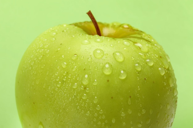 Primo piano di gocce d'acqua sulla mela verde fresca su sfondo verde green