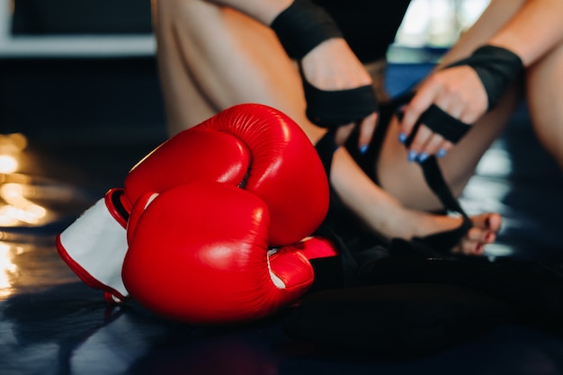 Primo piano di guanti da boxe rossi sul pavimento di un ring di pugilato blu.