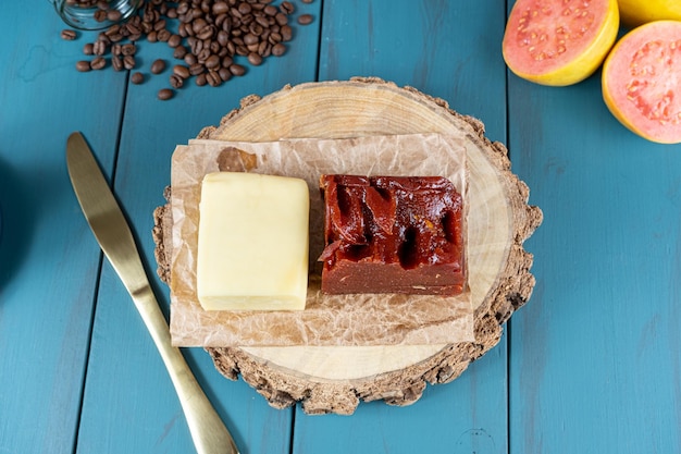 Primo piano di guava dolce con formaggio su una tavola di legno accanto a una tazza di coltello e una vista di chicchi di caffè