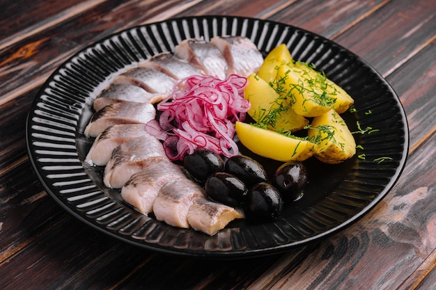 Primo piano di gustose aringhe marinate con patate e cipolle nel piatto