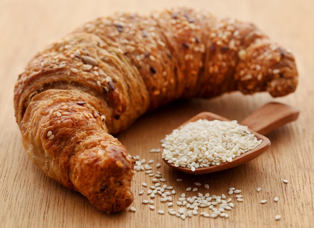 Primo piano di gustoso croissant con semi di sesamo in un cucchiaio