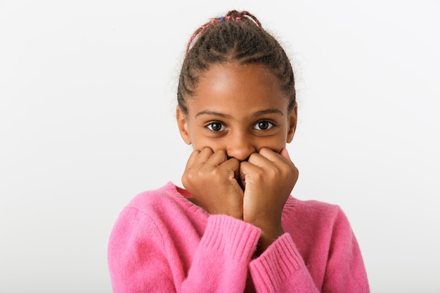 Primo piano di immagine della ragazza afroamericana spaventata che esamina macchina fotografica isolata sopra la parete bianca