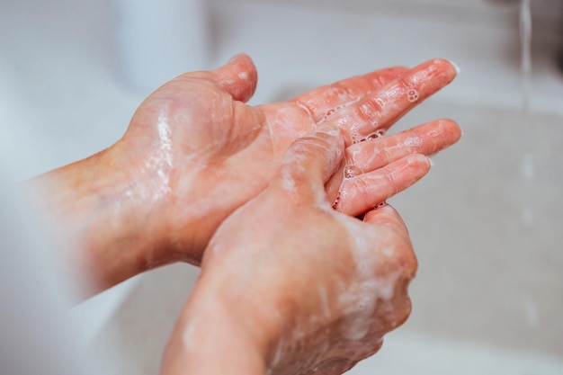 Primo piano di lavarsi le mani con sapone in bagno