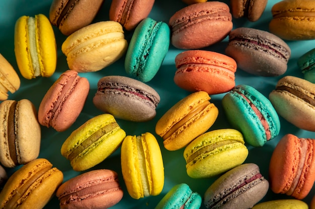 Primo piano di macarons torte di diversi colori su sfondo blu Concetto culinario e di cucina Gustosi amaretti colorati