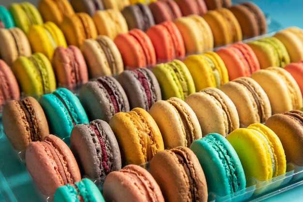 Primo piano di macarons torte di diversi colori su sfondo blu Concetto culinario e di cucina Gustosi amaretti colorati