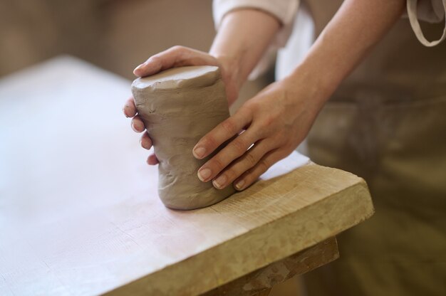 Primo piano di mani femminili che modellano la forma di un vaso