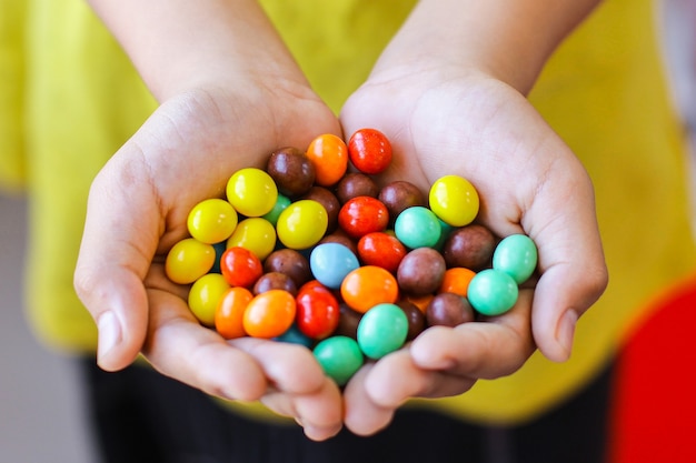 Primo piano di mani piene di pillole colorate di caramelle al cioccolato